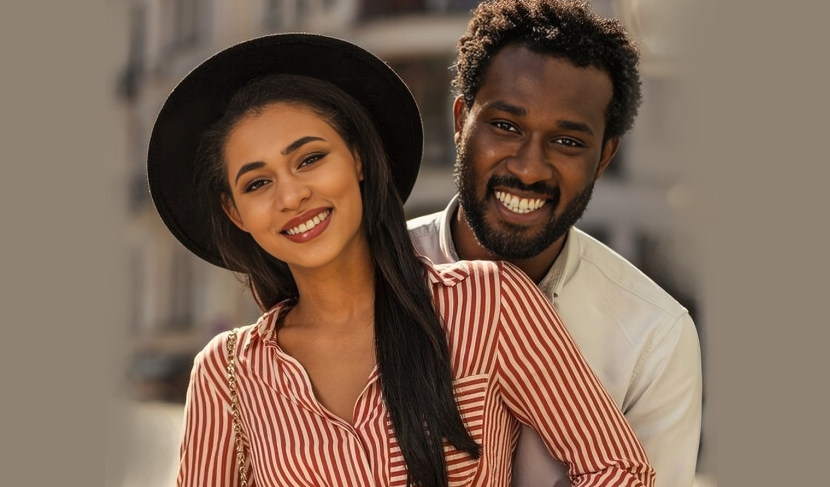 Two smiling people wearing matching red striped shirts pose together indoors against neutral background.